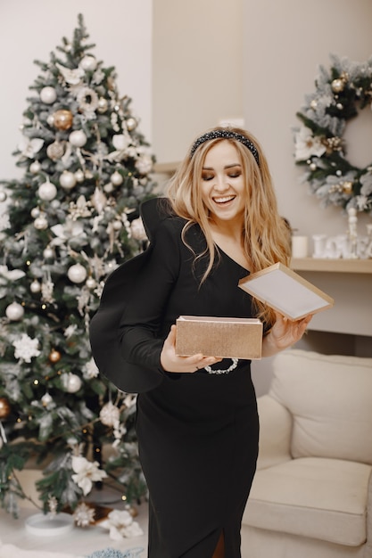 Señora elegante cerca del árbol de Navidad. Mujer en una habitación. Famale con un elegante vestido negro.