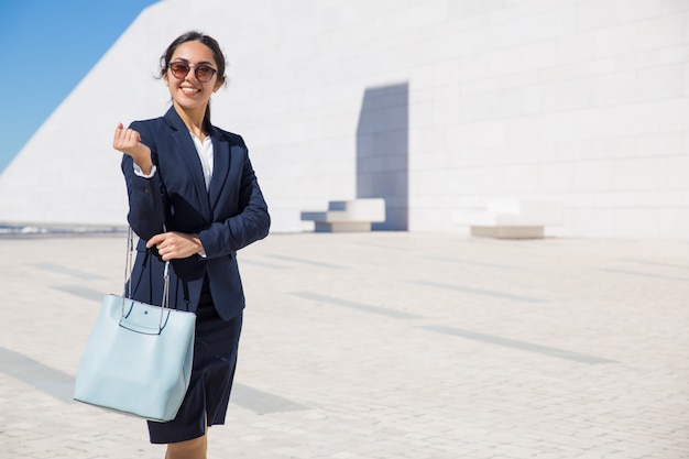 Señora elegante feliz del negocio que se dirige a su oficina