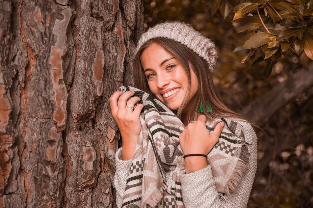 Señora encantadora cerca del tronco del árbol