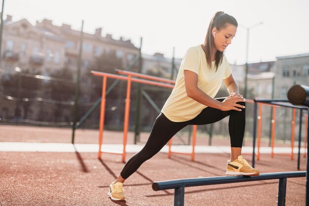 Señora enfocada en ropa deportiva estirando el cuerpo al aire libre