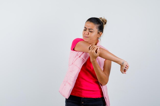 Señora estirando el brazo en camiseta, chaleco y mirando triste