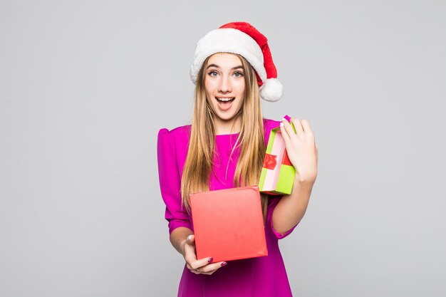 Señora feliz divertida muy sonriente en vestido rosa y sombrero de año nuevo con sorpresa de caja de papel en sus manos