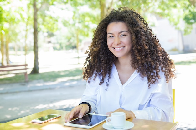 Señora feliz navegando en tablet PC en la mesa de café en el parque