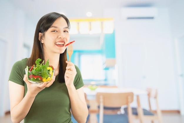 Señora feliz que sostiene cosas de la cocina sobre fondo del espacio de la copia