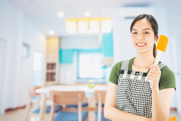 Señora feliz que sostiene cosas de la cocina sobre fondo del espacio de la copia