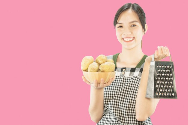 Señora feliz que sostiene cosas de la cocina sobre fondo del espacio de la copia