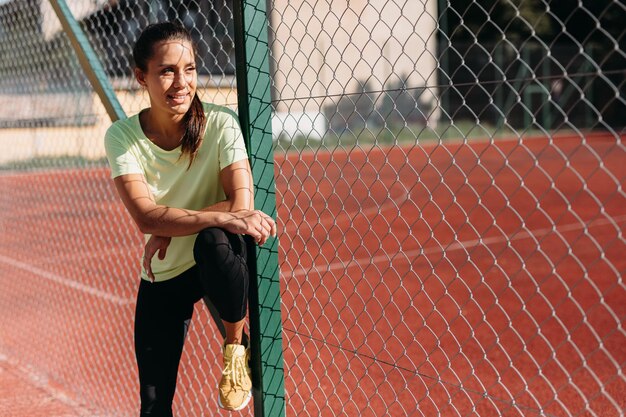 Señora feliz en ropa deportiva sonriendo y mirando a un lado