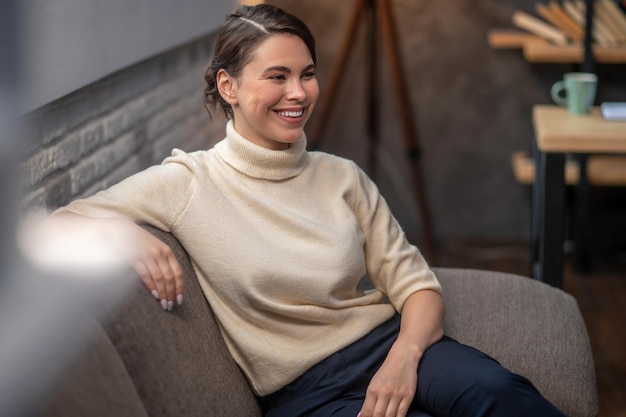 Señora feliz sentada en el sofá en el interior