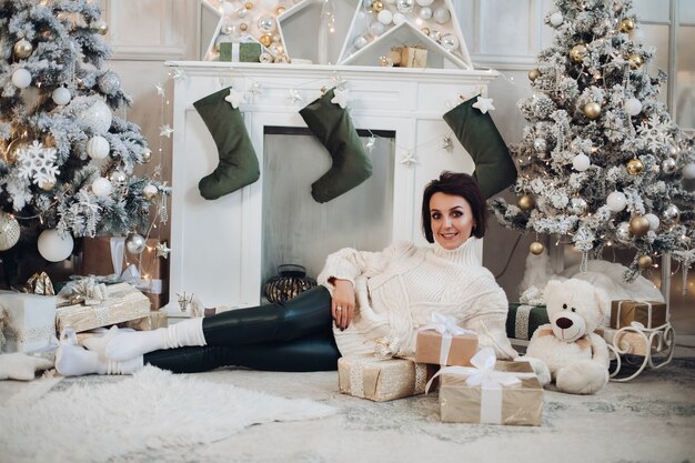 Señora feliz tirado en el suelo en casa en el fondo del árbol de Navidad