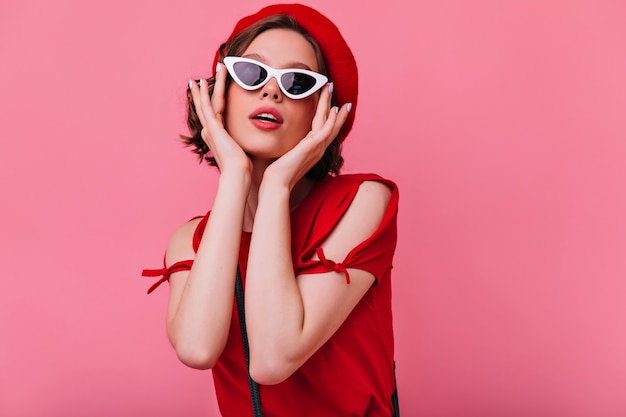 Señora francesa glamorosa tocando sus gafas de sol. magnífica mujer blanca con pelo corto ondulado.