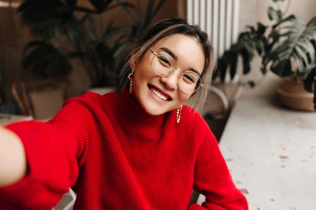 Señora con gafas y aretes enormes hace selfie