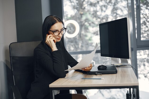 Señora con gafas. El gerente está sentado frente a la computadora. La empresaria trabaja en su oficina.