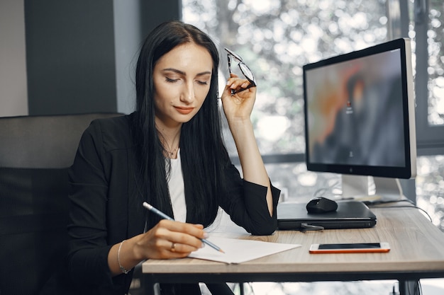 Señora con gafas. El gerente está sentado frente a la computadora. La empresaria trabaja en su oficina.