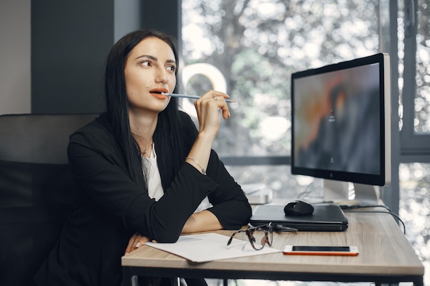 Señora con gafas. El gerente está sentado frente a la computadora. La empresaria trabaja en su oficina.