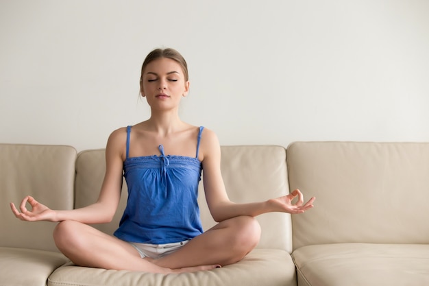 Señora haciendo ejercicios de yoga en casa por la mañana