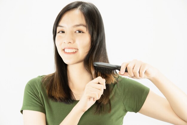 Señora hermosa joven feliz usando el peine para enderezar su pelo - concepto del cuidado del cabello de la belleza de la mujer