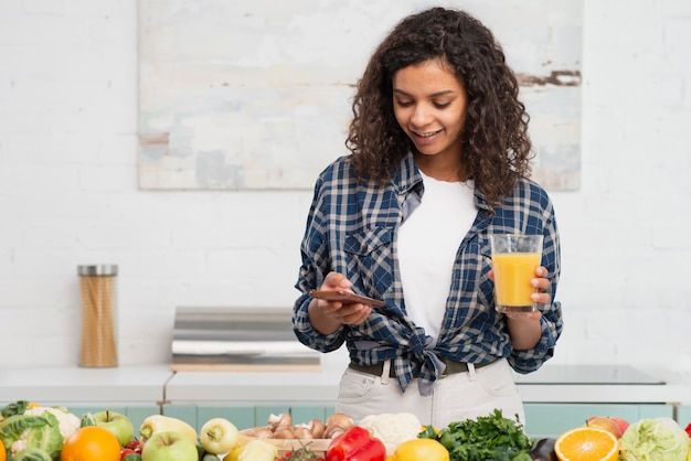 Foto gratuita señora hermosa que controla su teléfono al lado de verduras