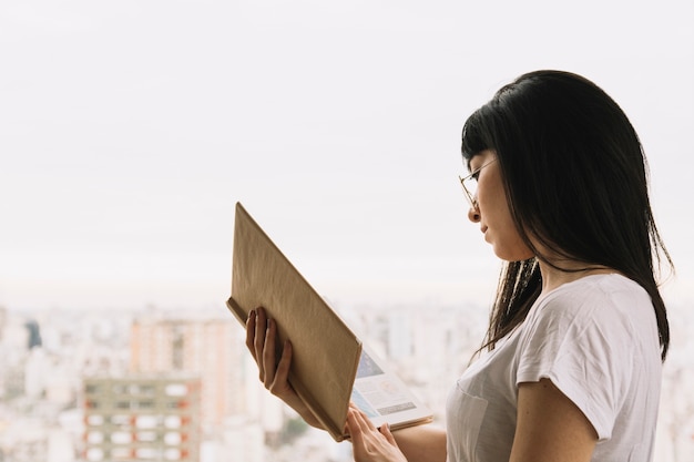 Foto gratuita señora inteligente leyendo cerca de la ventana