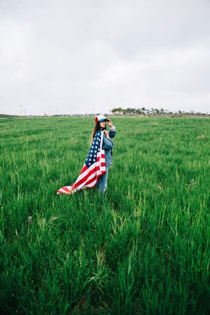 Señora joven con bandera estadounidense mirando a cámara