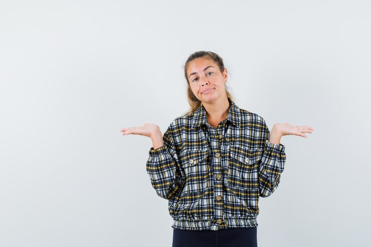 Foto gratuito señora joven en camisa a cuadros que muestra un gesto de impotencia y que parece confundido, vista frontal.