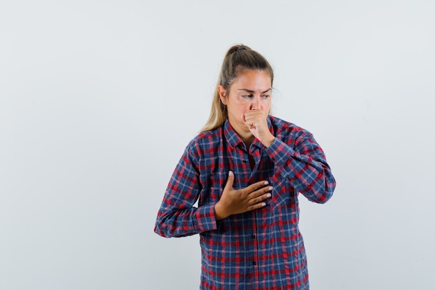 Foto gratuita señora joven en camisa a cuadros que sufre de tos y parece enferma, vista frontal.