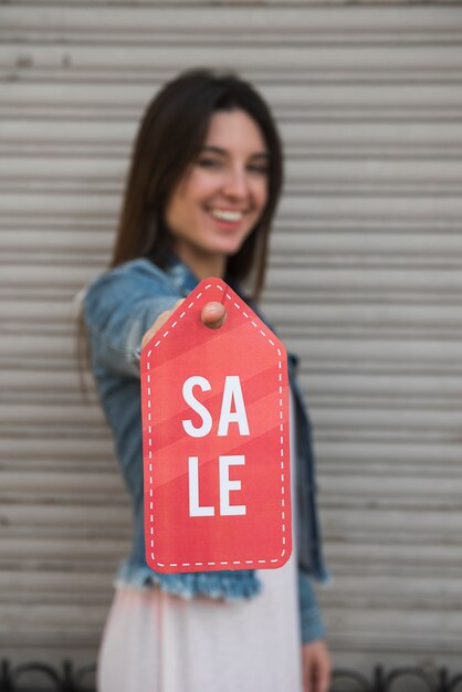 Señora joven feliz con la tableta de la venta cerca de la pared que cubre perfilada