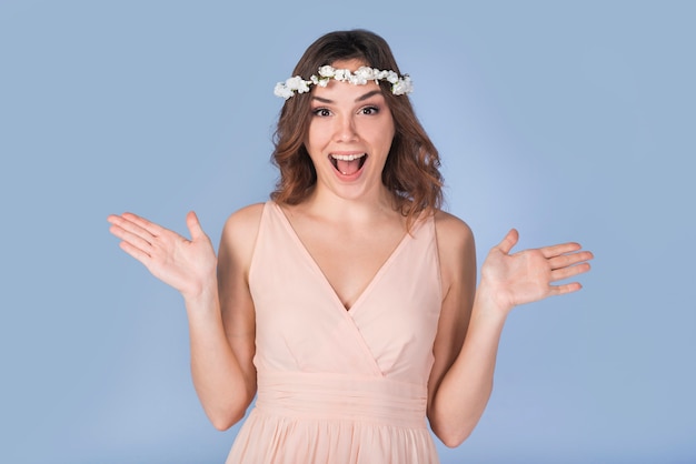 Señora joven gritadora feliz en vestido con la guirnalda blanca en la cabeza