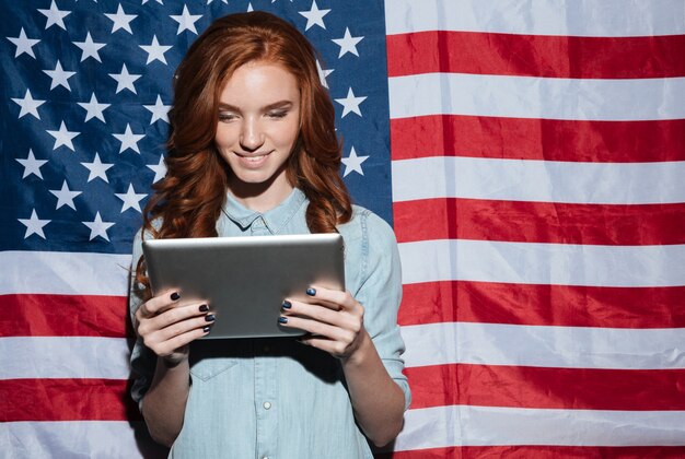 Señora joven pelirroja feliz con tablet PC.