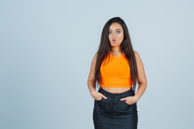 Señora joven que muestra la cara de pescado con la boca en camiseta, minifalda y un aspecto divertido. vista frontal.