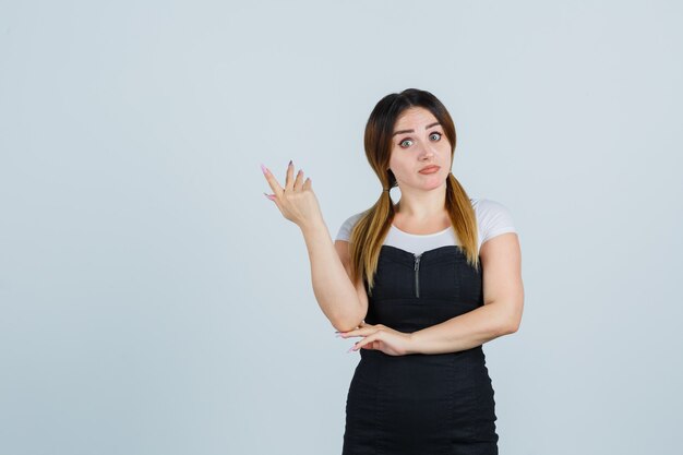 Señora joven rubia en vestido gesticulando aislado