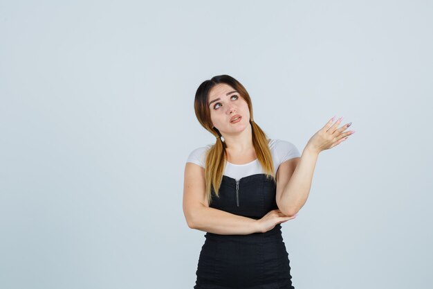 Señora joven rubia en vestido gesticulando aislado