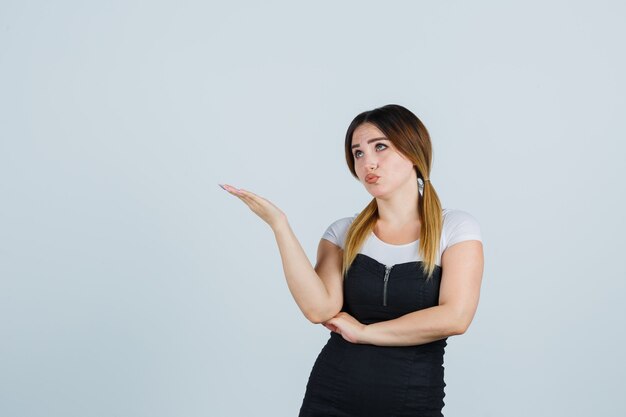 Señora joven rubia en vestido gesticulando aislado