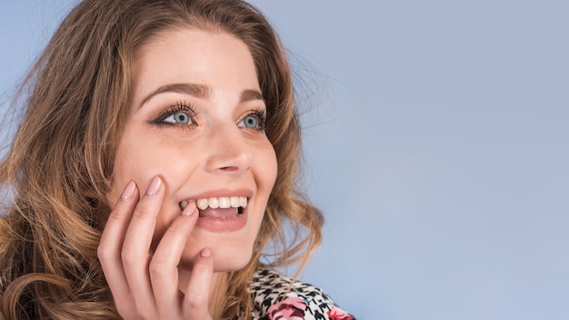 Foto gratuita señora joven soñadora positiva con la mano en mejilla