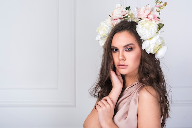 Señora joven en vestido con flores frescas en la cabeza