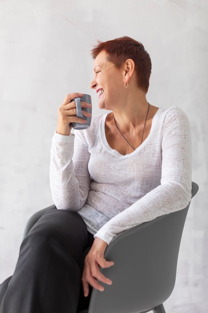 Señora madura delantera con taza mirando a otro lado