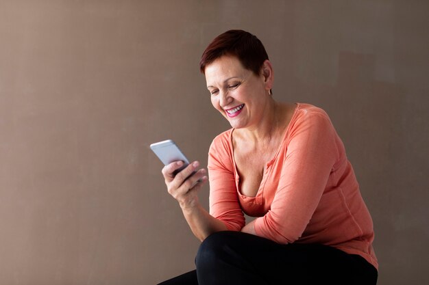 Señora madura sonriente con smartphone