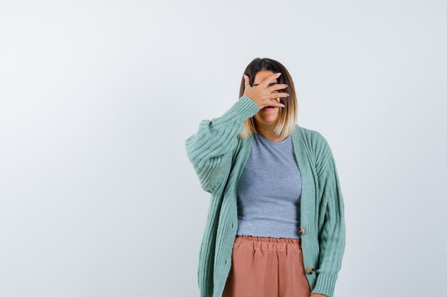 Señora manteniendo la mano en los ojos con ropa casual y mirando asustada. vista frontal.