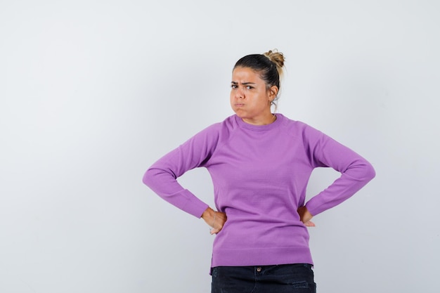 Foto gratuita señora manteniendo las manos en la cintura con blusa de lana y mirando rencorosa