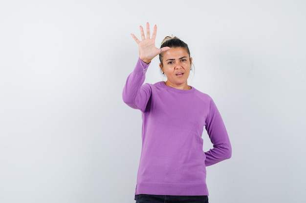 Señora mostrando cinco dedos en blusa de lana y mirando confiado