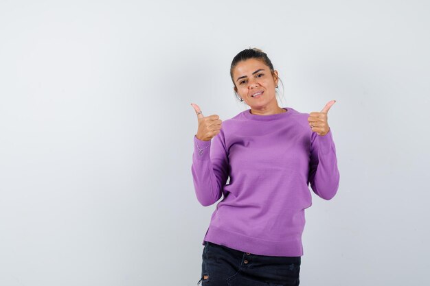 Señora mostrando doble pulgar hacia arriba en blusa de lana y mirando alegre