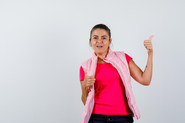 Señora mostrando doble pulgar hacia arriba en camiseta, chaleco y mirando feliz