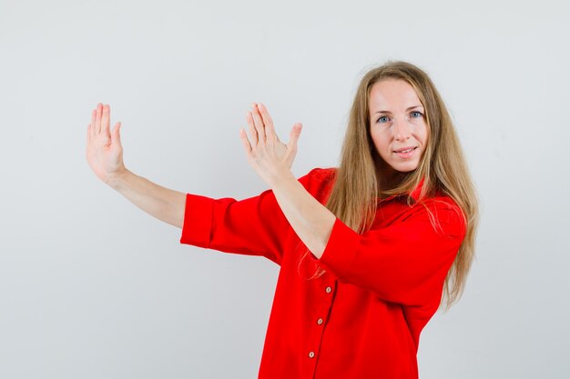 Señora mostrando gesto de chuleta de karate en camisa roja y mirando confiado,