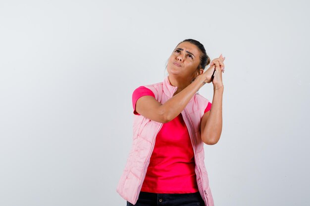 Señora mostrando gesto de pistola en camiseta, chaleco y mirando pensativo