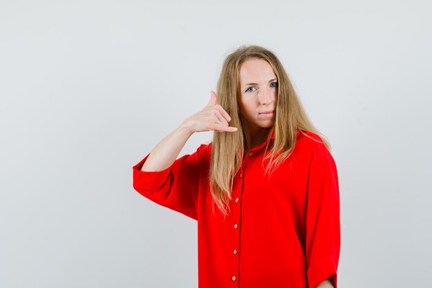 Señora mostrando gesto de teléfono en camisa roja y mirando confiado,