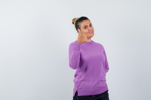 Señora mostrando el pulgar hacia arriba en una blusa de lana y mirando confiada