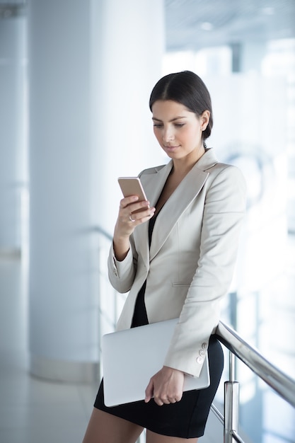 Foto gratuita señora de negocios de contenido con smartphone y portátil