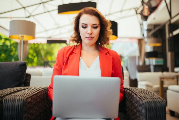 Señora de negocios exitosa mujer linda usando la computadora portátil mientras está sentado en el café salón.