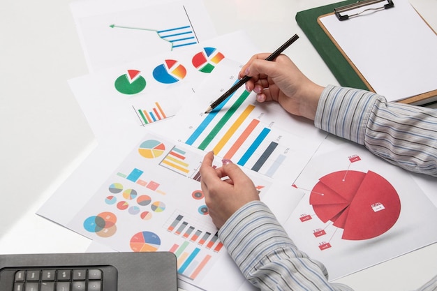 Foto gratuita señora de negocios de marketing en camisa a rayas en la oficina con computadora sosteniendo lápiz en gráficos