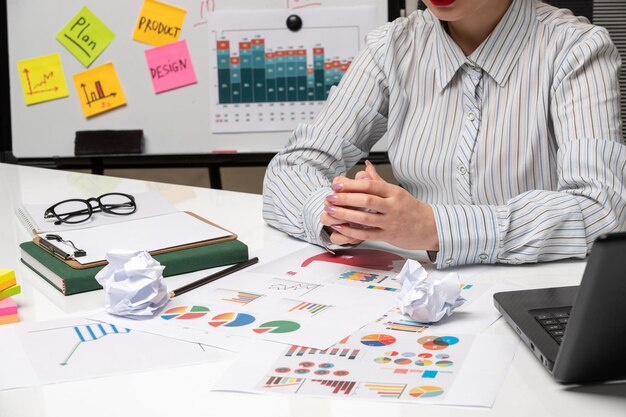 Señora de negocios de marketing en camisa a rayas en la oficina con gafas en el escritorio cruzando las manos con taza