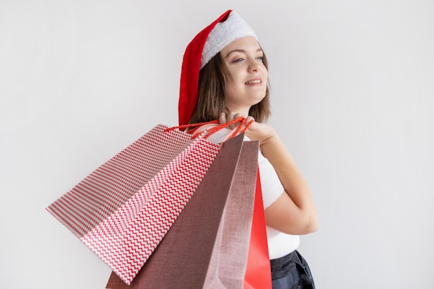 Señora pensativa sonriente que sostiene bolsos de compras en hombro